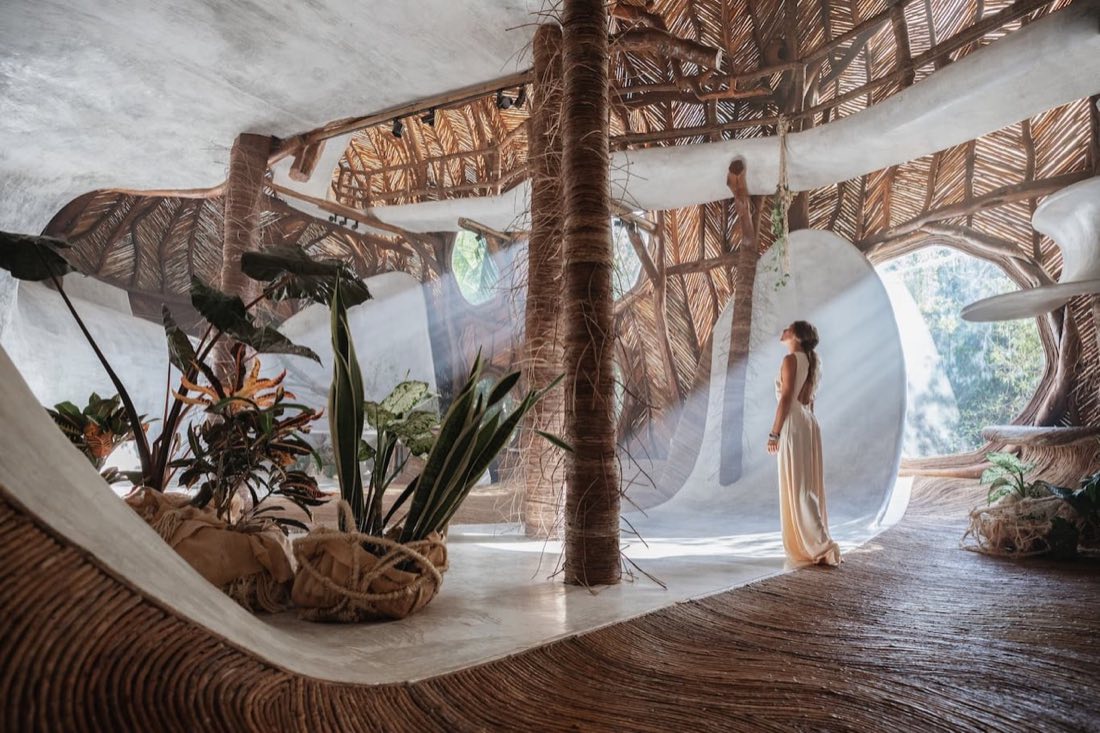 Woman in a flowing dress inside organic architecture interior