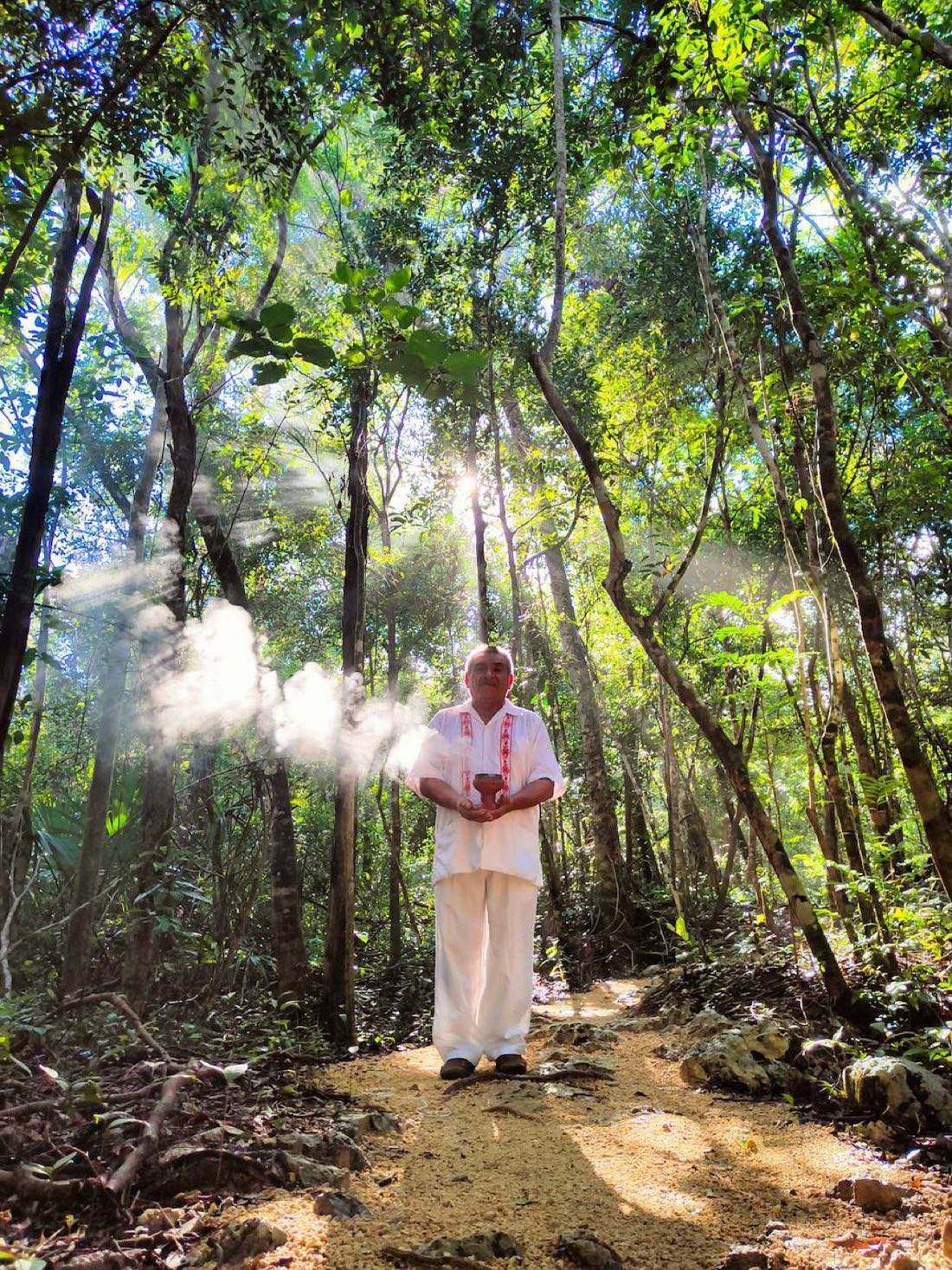 Maya guide with smoking copal on a sunlit jungle path
