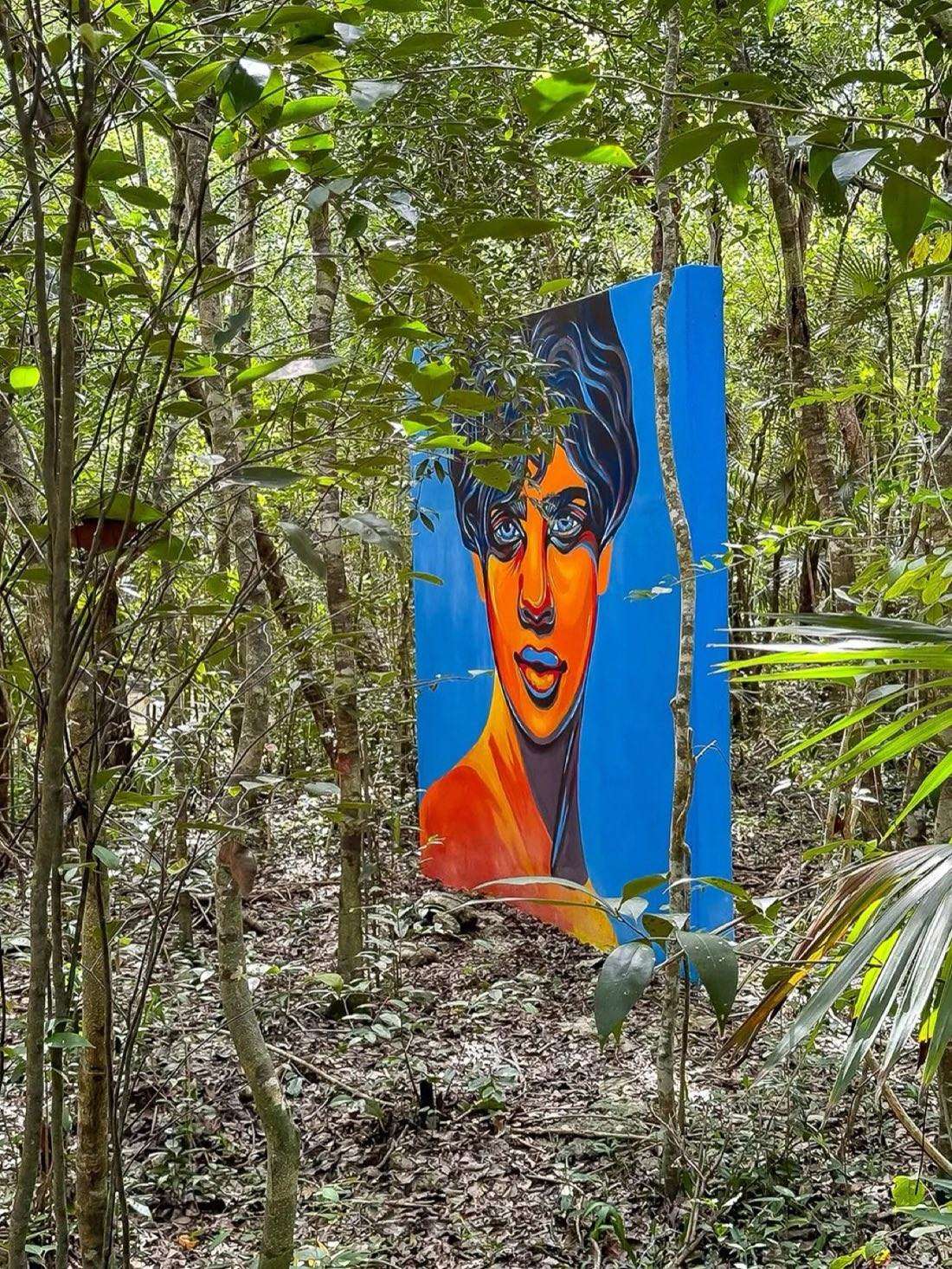 Vivid portrait mural standing among lush jungle trees