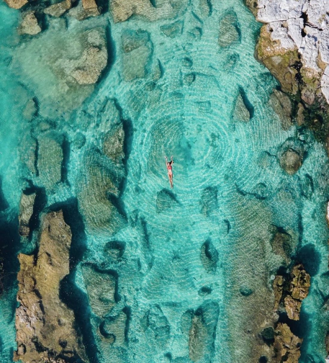 Aerial view of a woman floating in turquoise water