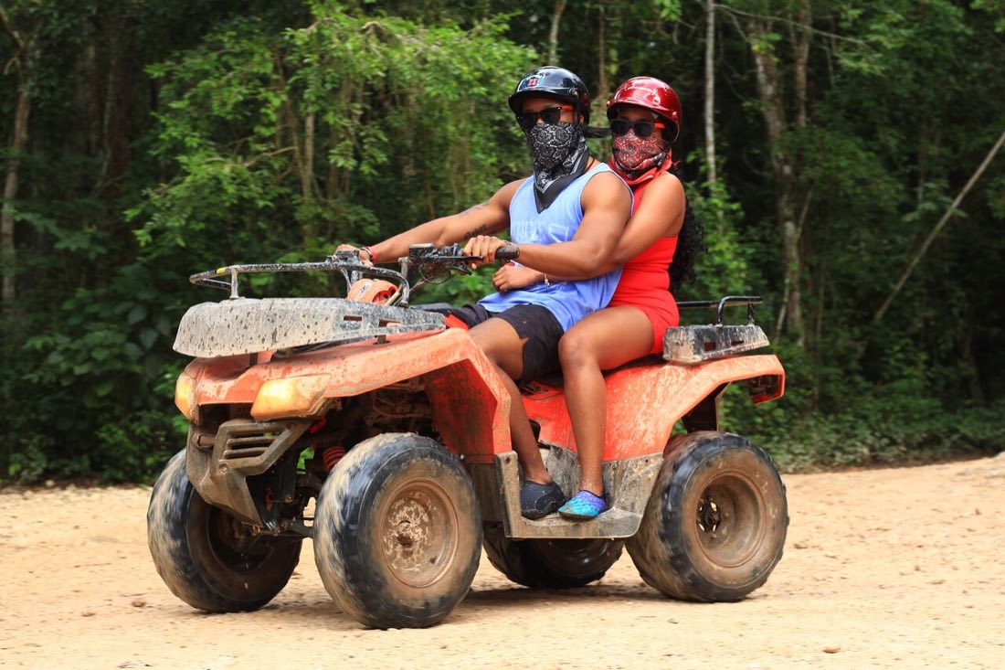 Two riders on a quad bike along a jungle trail