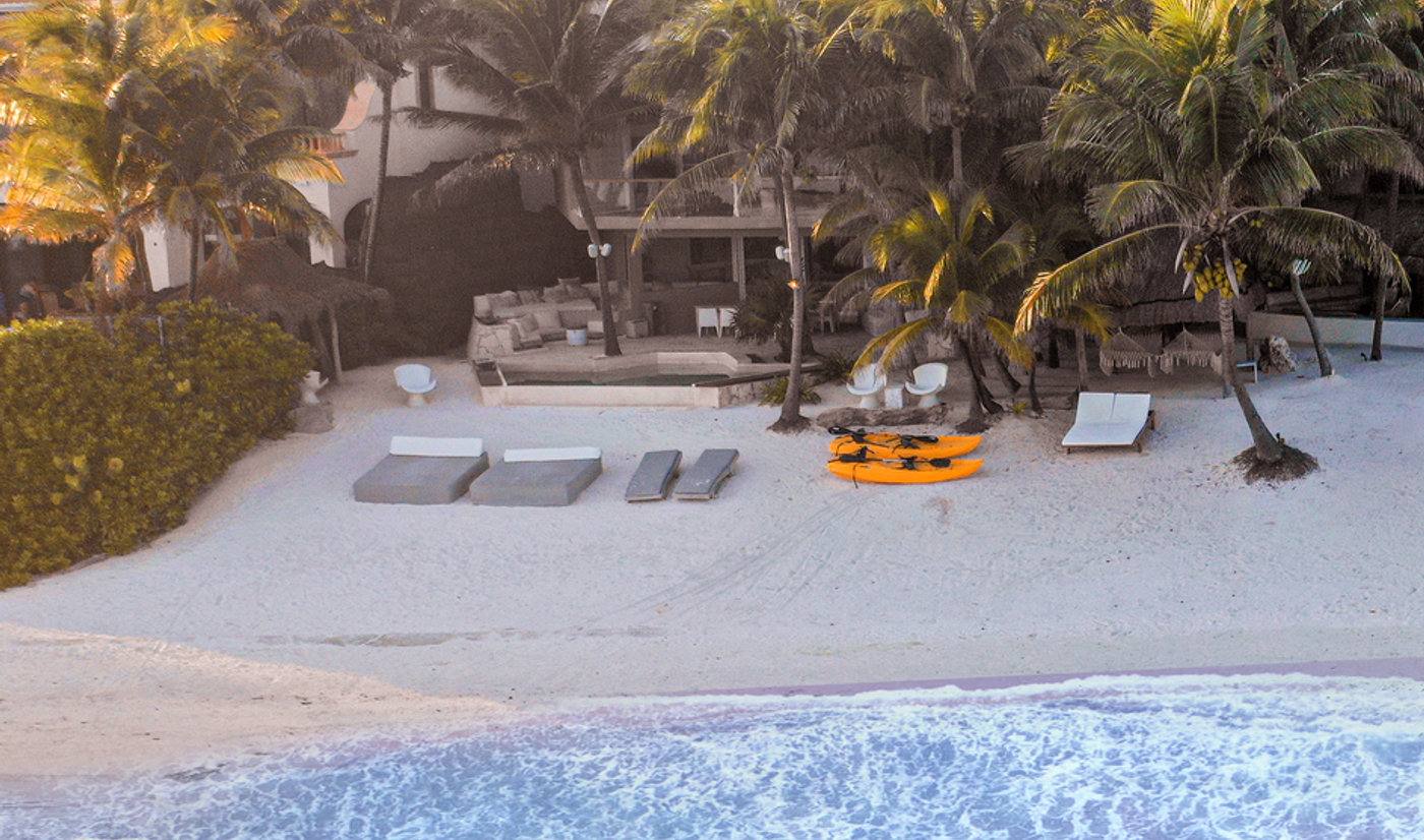 Aerial view of beachfront villa with orange kayaks on sand